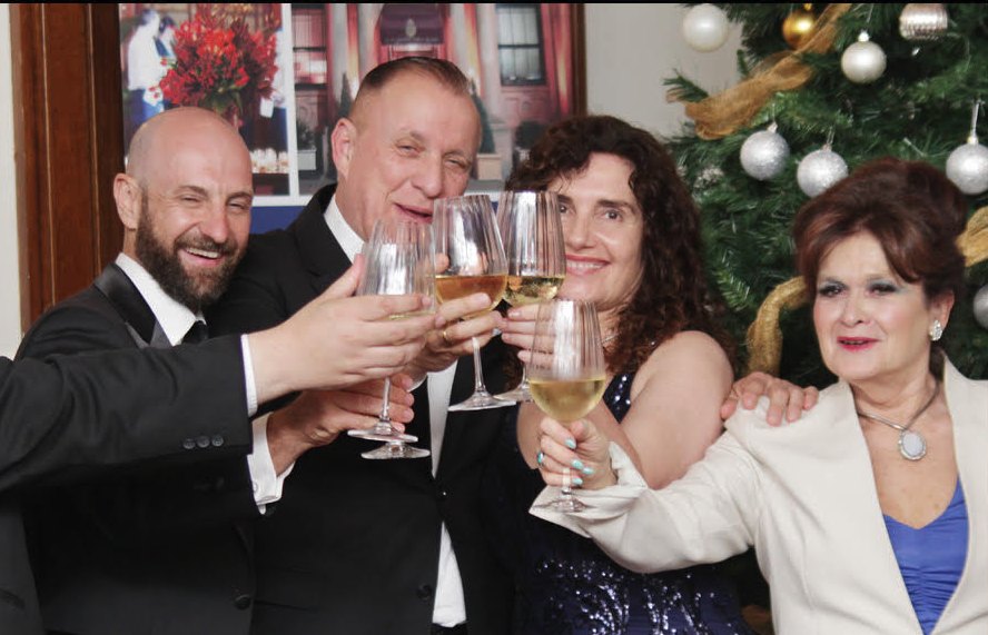 Carl raising a glass with members in front of the Club's Christmas tree